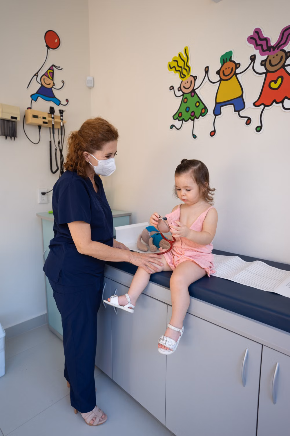 Pediatric nurse examining a young child in a clinic office